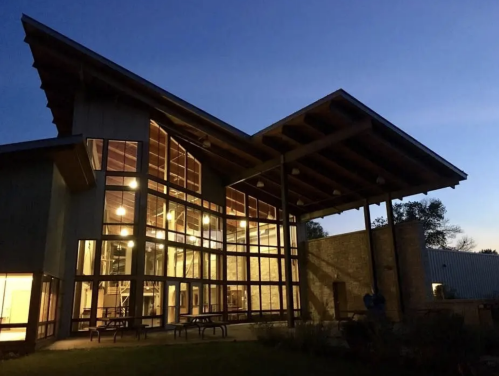 Photo of The Nature Place at night with lights shining through the large windows.